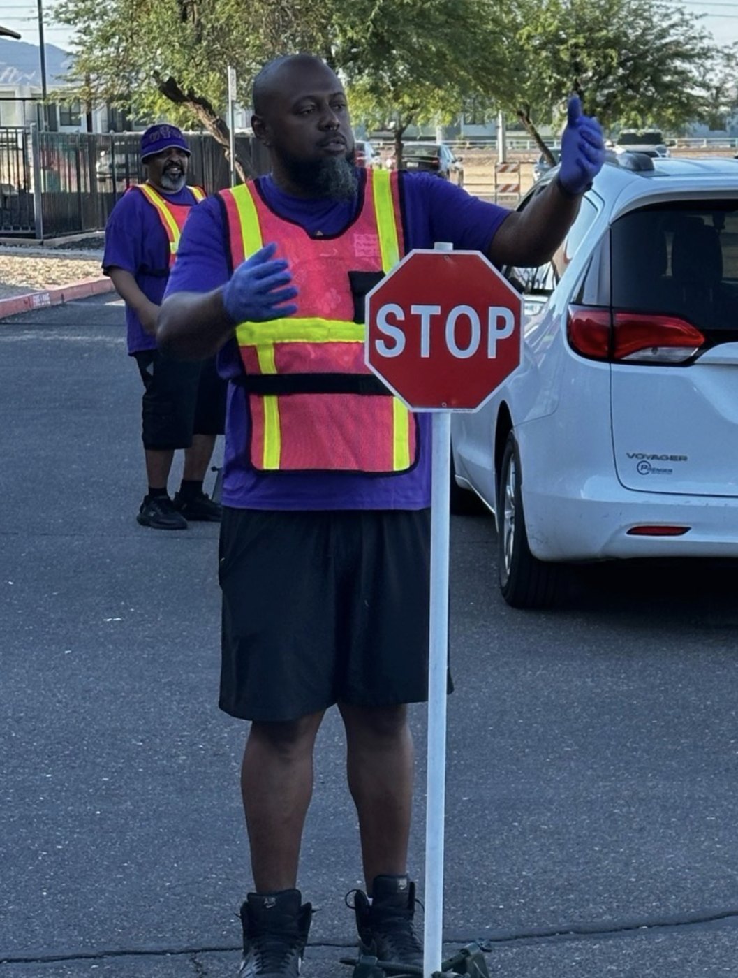A volunteer directing traffic at a drive-through distribution